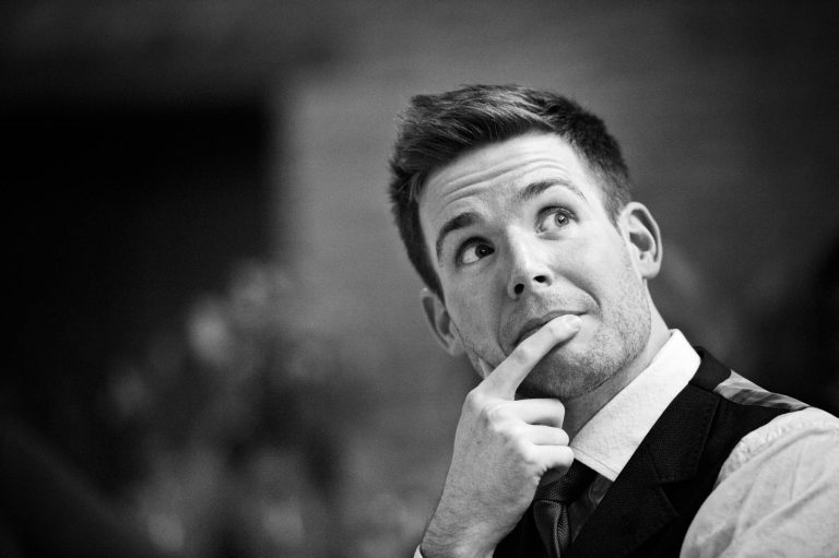 Candid photo of groom during speeches at Kingscote Barn