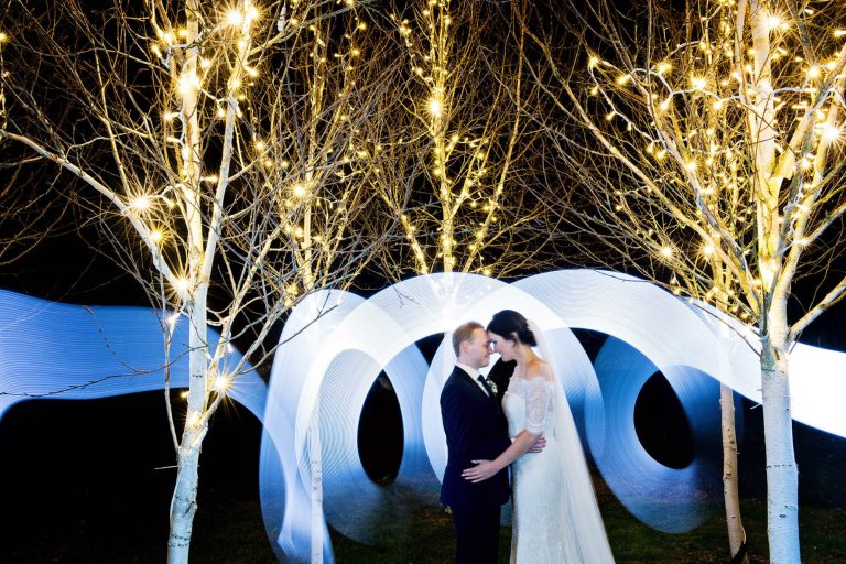 Bride and groom pose with lights at Kingscote Barn