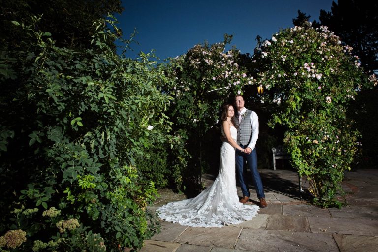 Evening photo of bride and groom in the rose garden at Kingscote Barn