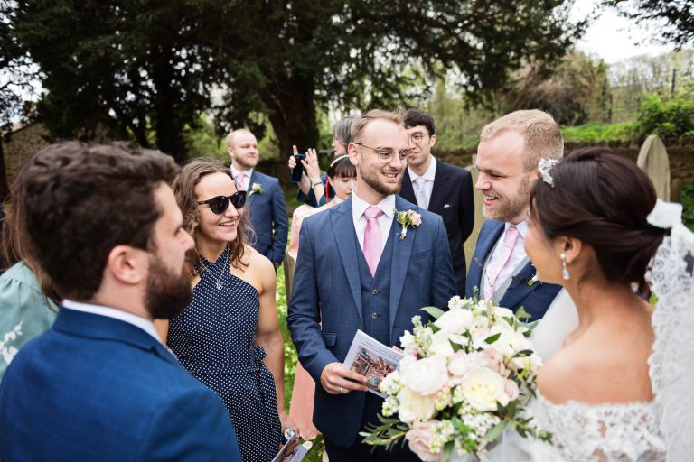 Bride and groom chat and exchange stories in the church grounds. Story telling photograph by Blooming Photography.
