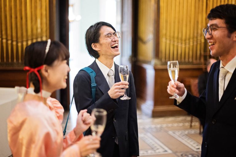 Guest laugh together whilst drinking champagne. Photograph by Blooming Photography.