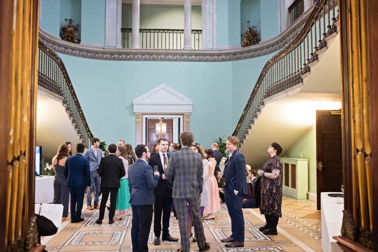 Guests stand in Leigh Court's Grand Hall. Candid photograph by Blooming Photography.