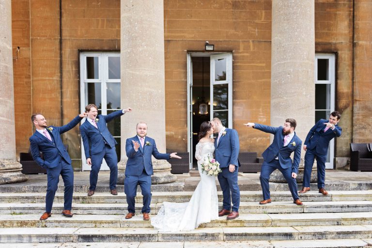 Groomsmen on the steps of Leigh Court point at the bride and groom.