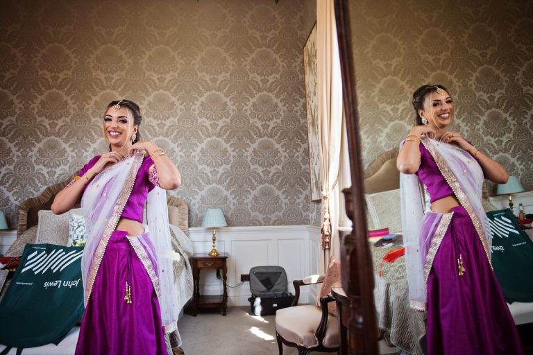 Bridesmaid getting ready in reflection of mirror at North Mymms Park, candidly photographed by Blooming Photography