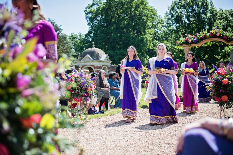 Bridesmaids entrance carrying gifts at North Mymms Park, candidly photographed by Blooming Photography. Colourful.