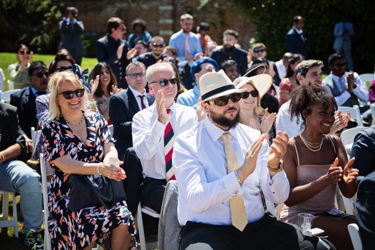 Guests clapping and cheering after the Hindu ceremony at North Mymms Park, candidly photographed by Blooming Photography.