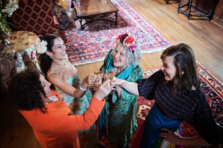 Guests cheering each other in the great hall, photographed from above. At North Mymms Park, candidly photographed by Blooming Photography.