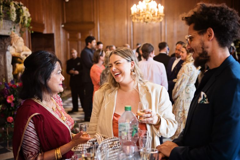 Guests chat and laugh together at North Mymms Park, candidly photographed by Blooming Photography.