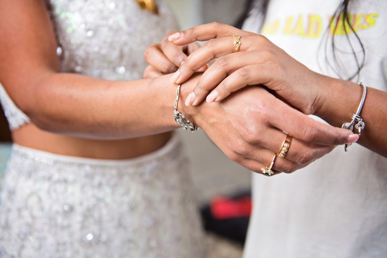 Close up of wedding bracelets being put on a brides wrist. Taken at North Mymms Park, candidly photographed by Blooming Photography.