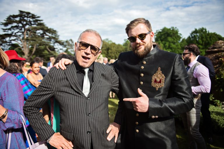 A well dressed older man poses with the groom at a wedding. Both look very cool and are wearing shades. Photographed at North Mymms Park, by Blooming Photography.