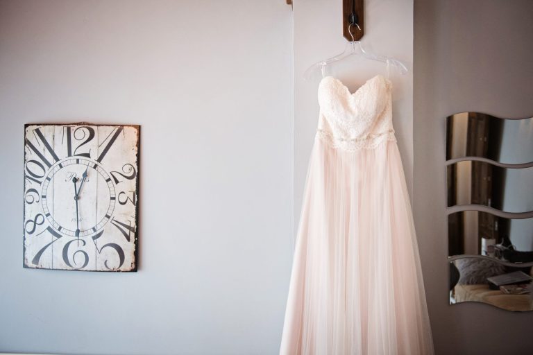 Wedding dress hung up next to a clock. Time for a wedding.