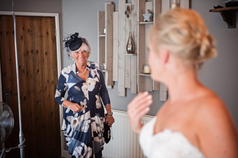 Documentary photo of brides mother seeing her daughter for the first time in a wedding dress.
