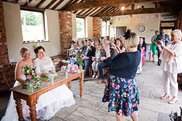 Guests taking photos of the bride and bride after the signing of the register.
