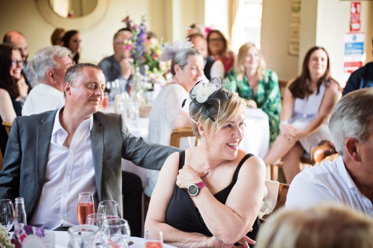 Wedding guests smile during the wedding speeches.