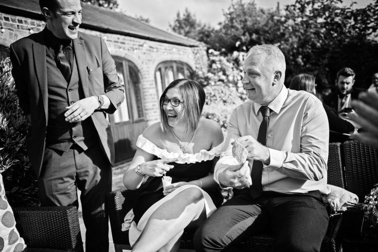 B&W photo of wedding guests getting wowed by the magician's magic trick