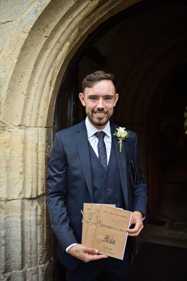 Groomsman holding the order of service.