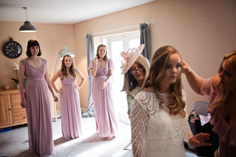 Bridesmaids watch on at the bride having the final details added by the mother of the bride.