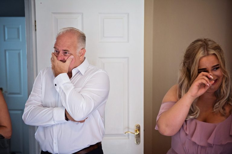 Dad and a bridesmaid, cry with happy emotion after seeing the bride in her wedding dress for the first time.