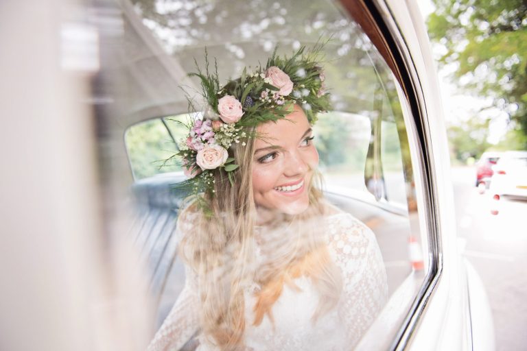 Amazing candid photo of bride looking out through the window of her wedding car. Bride is smiling and looking excited.