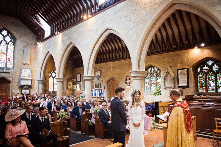 Overview of the bride and groom saying their wedding vows with the congregation aka wedding guests sat behind them.