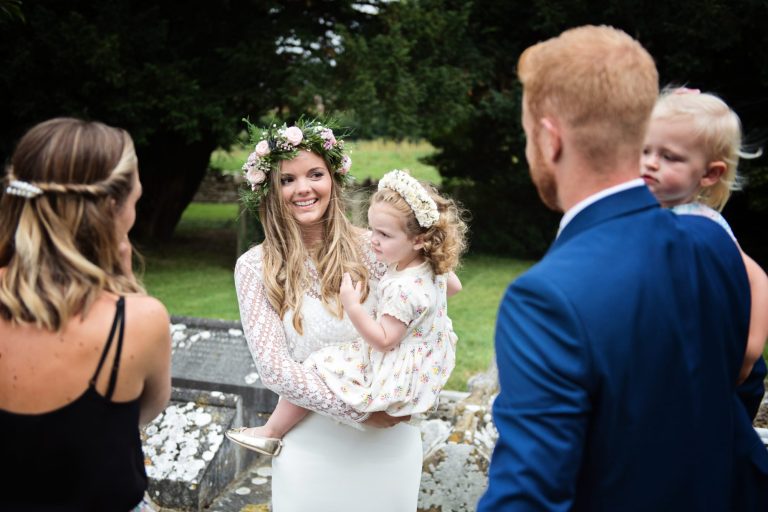 Candid image of bride (holding her daughter), chatting to guests.