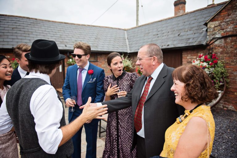 Candid wedding photo of guests laughing at Gloucestershire magician Darren Campbell at Overbarn, Gloucester