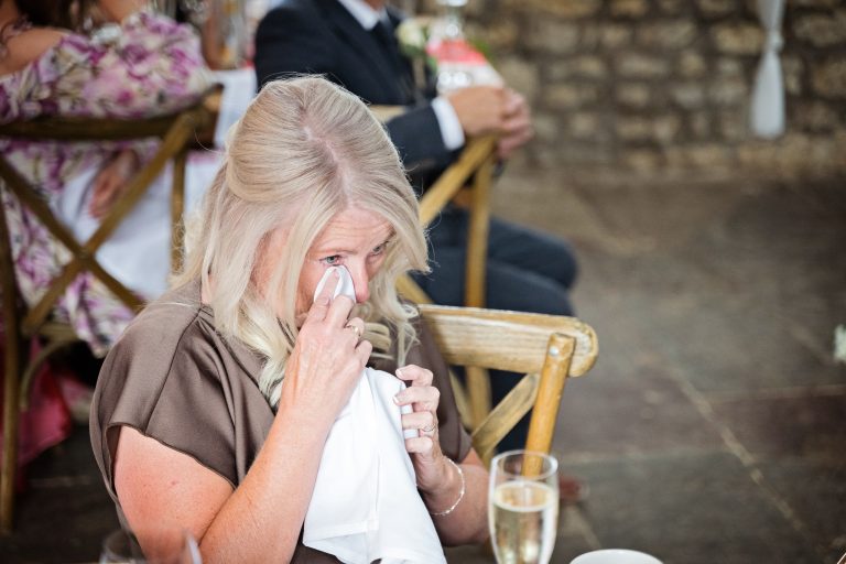 mother of the bride crying and using a napkin to wipe her teary eye
