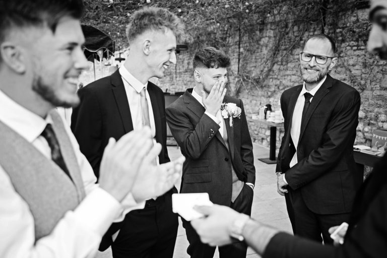A b&w image of magician entertaining wedding guests