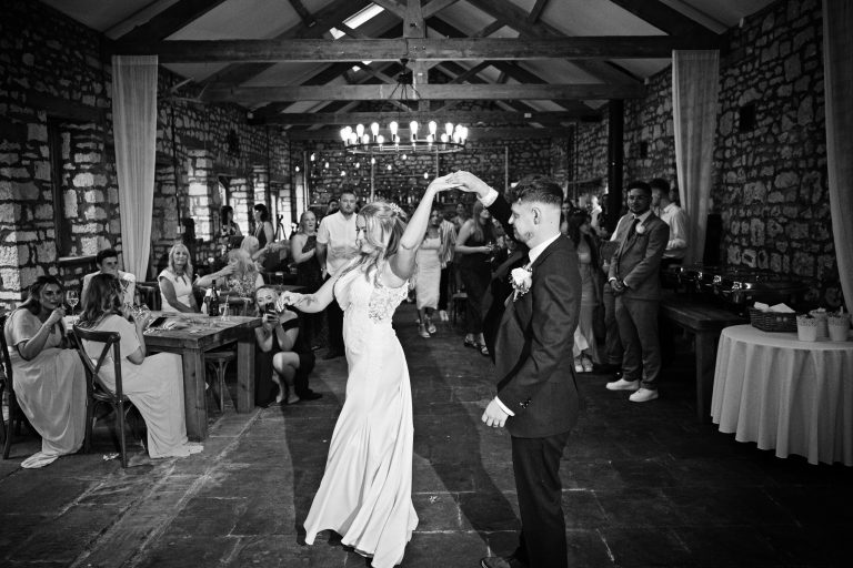 B & W Image of Bride & Groom doing a twirl on their first dance.