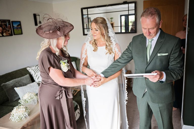 mother of the bride, bride and father of the bride holding hands