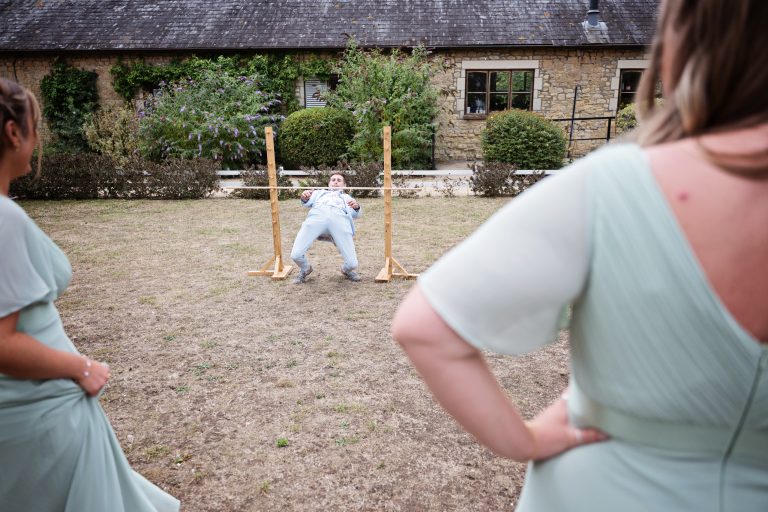 A wedding guest doing an impressive limbo. back of bridesmaids looking on impressed