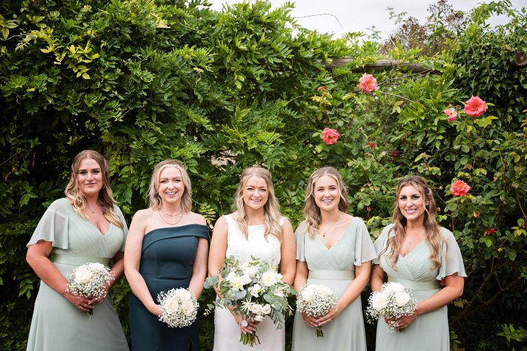 bridesmaids stand smiling holding their wedding flowers