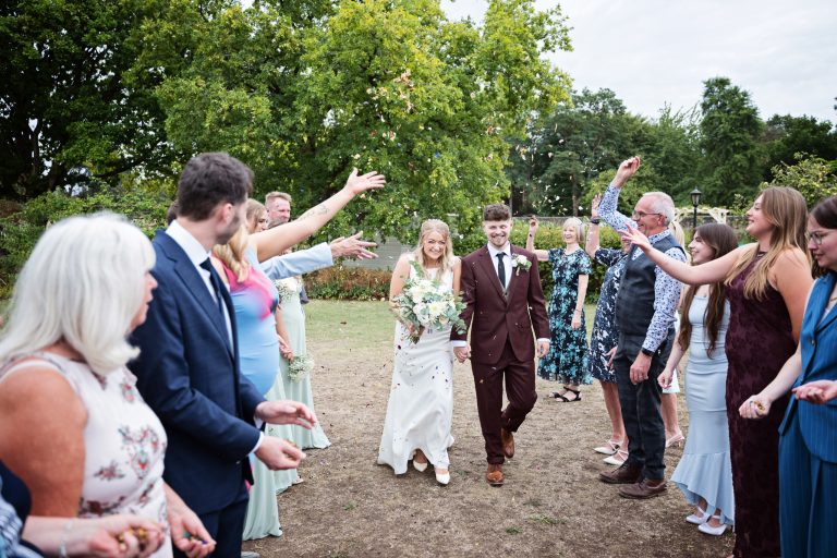 bride and groom walking down a isle with confetti being thrown at them