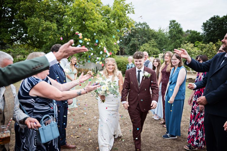 bride and groom walking down a isle with confetti being thrown at them