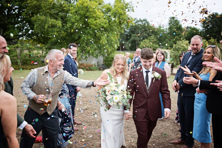 bride and groom walking down a isle with confetti being thrown at them