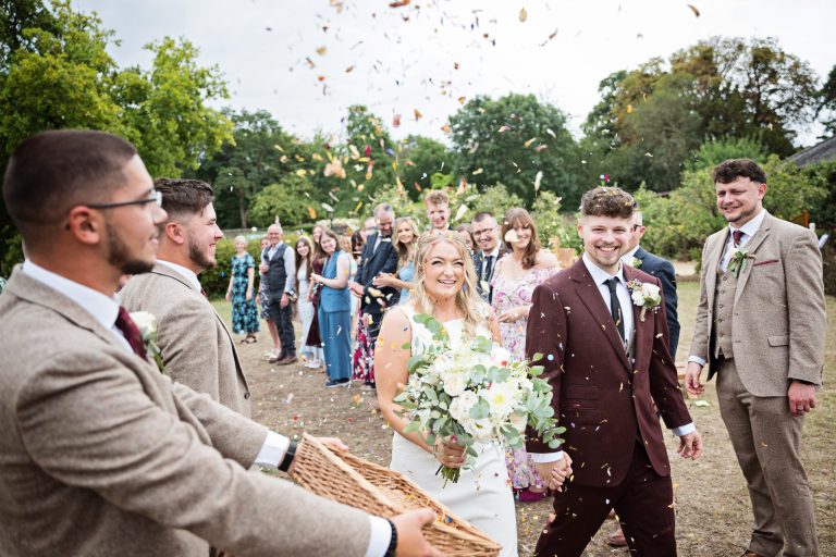 bride and groom walking down a isle with confetti being thrown at them