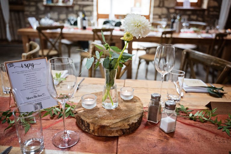 A rustic wedding table set up complete with white dahlias, candles and wooden table settings