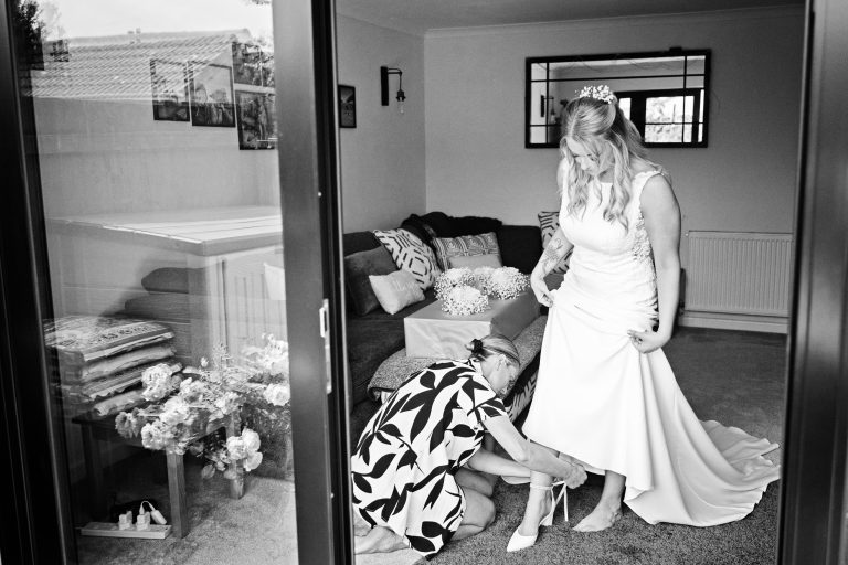 b&w image of a bride having her shoes put on