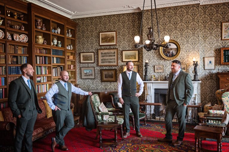 Photo of groomsmen standing, smiling at each other in a Georgian library.