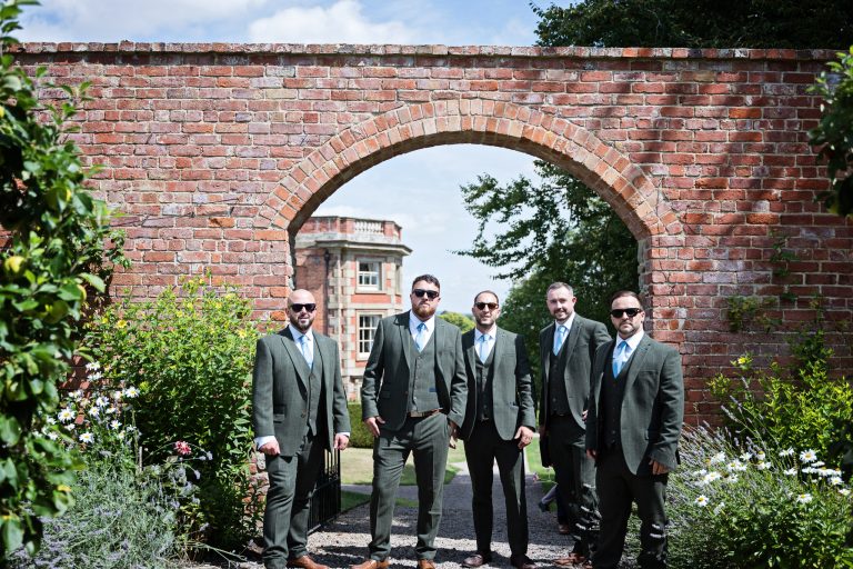 Photo of groom and his groomsmen standing in front of a Georgian garden wall. Looking cool