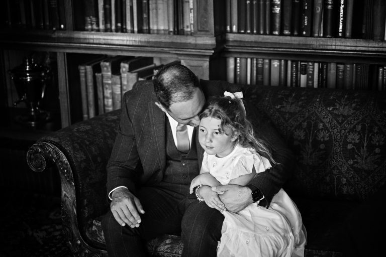 A b&w image of a dad hugging his daughter in a library