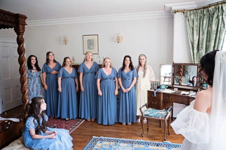 Bridesmaid and flower girls emotionally look at the bride in her wedding dress