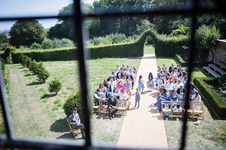 looking down out of stained glass window down onto guests seated at a wedding