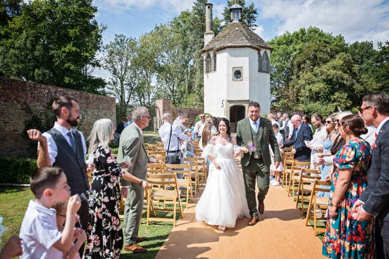 A bride and groom walk down a confetti isle
