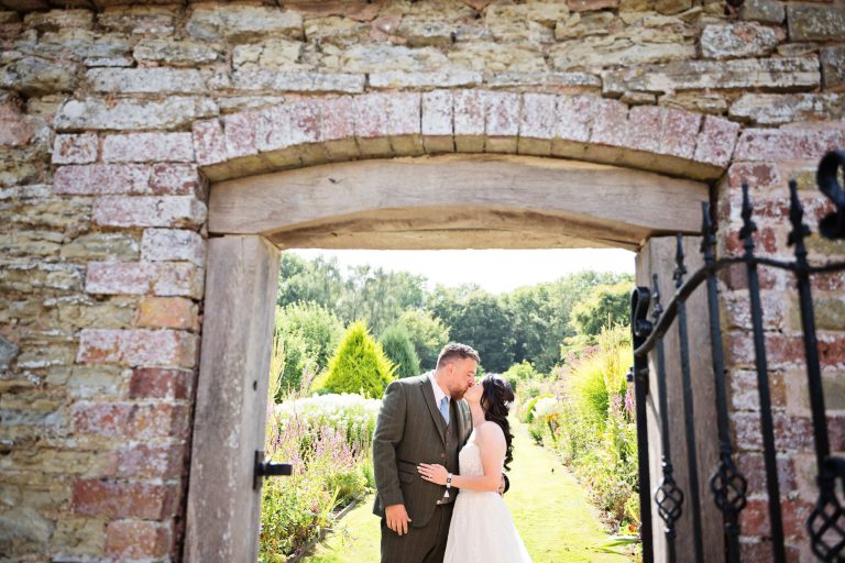 Natural wedding photography of a bride and groom kissing in the gardens of Homme House