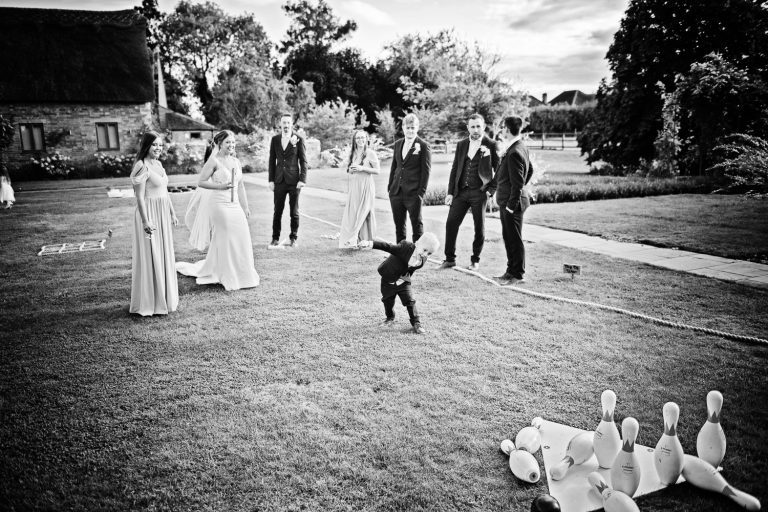 B&W image of wedding party relaxing and playing skittles.