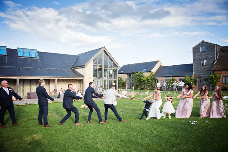 Wedding guests doing a tug of war on a lawn with Blackwell Grange in the foreground.
