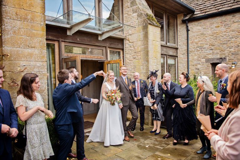 Bride and groom enjoy having confetti thrown over them at Calcot Manor.