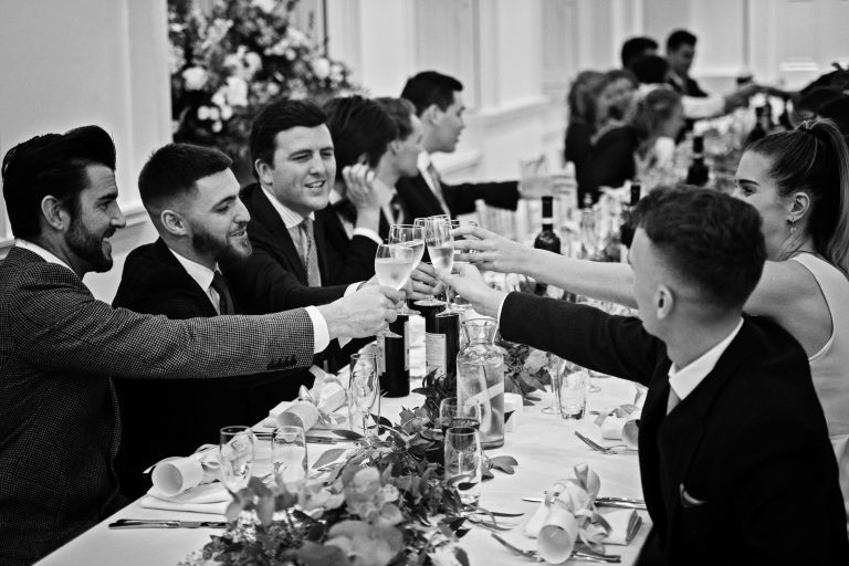 B&W photo of wedding guests raising their glass together