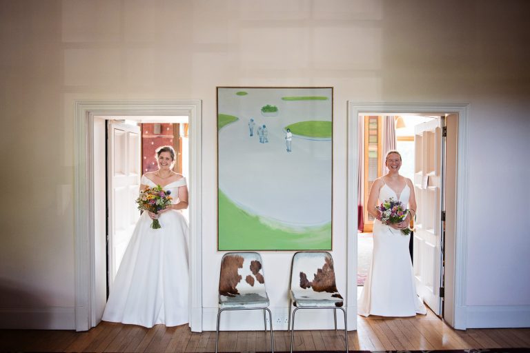 Bride and bride stand in two separate doorways for their first look (at each other).